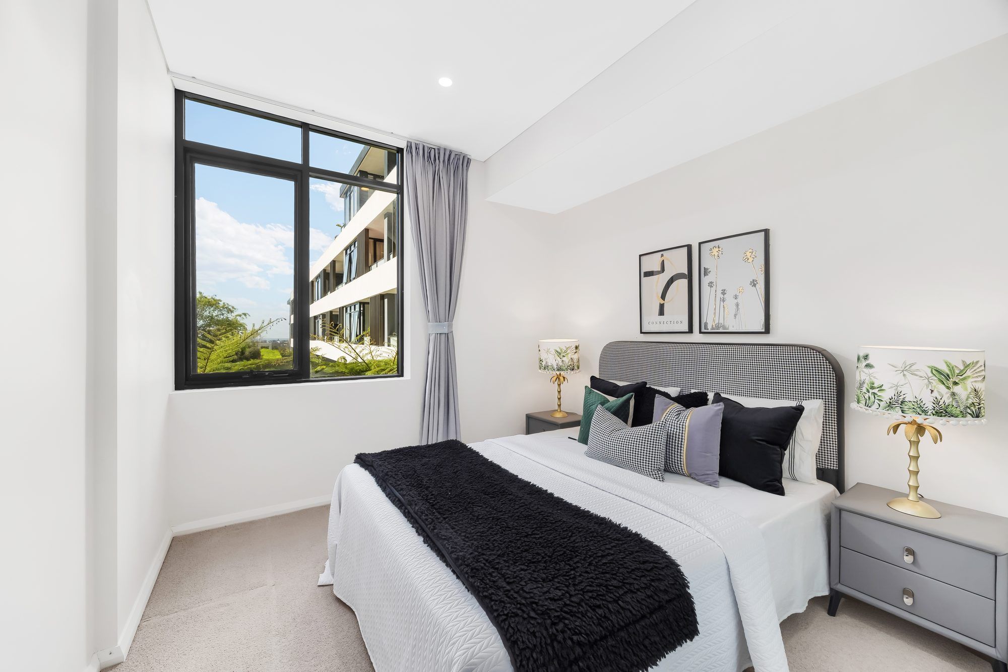 Bright apartment bedroom with a queen bed and a garden outlook